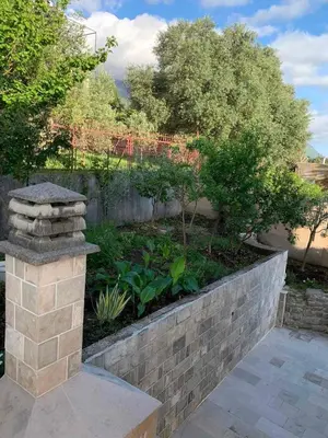 a garden with a retaining wall and a stone pillar at Villa Andrea Lower Level in Kavač