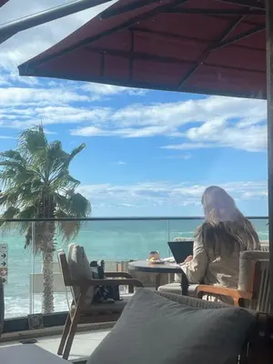 a woman sitting at a table looking out at the ocean at Montebay Studio in Dobra Voda