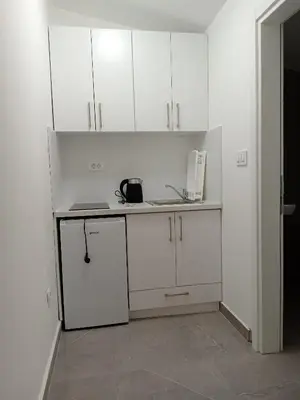 a white kitchen with white cabinets and a microwave at Martins Apartments in Dobra Voda