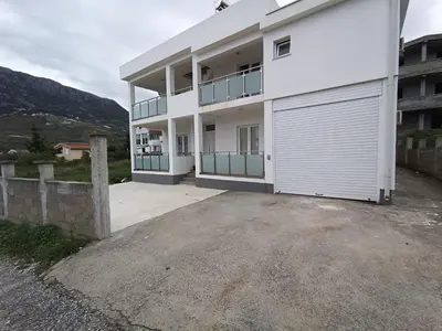 a large white building with a garage at Martins Apartments in Dobra Voda