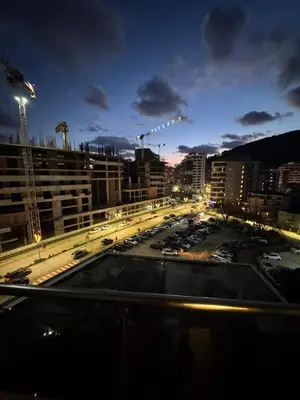 a city at night with cars parked in a parking lot at Modern Apartment Near the Beach - Budva in Budva