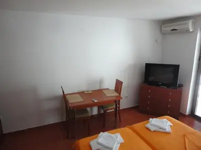 a room with a table and a tv and a table and chairs at Apart Ludmila in Becici