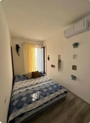 a bedroom with a bed with a blue checked blanket at Studio KIKA in Tivat