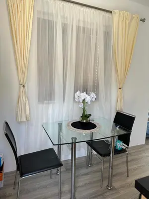 a glass table with two chairs and a vase with flowers at Studio KIKA in Tivat