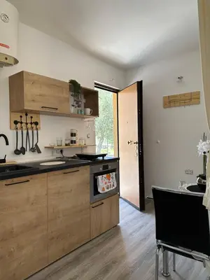 a kitchen with wooden cabinets and a table in it at Studio KIKA in Tivat