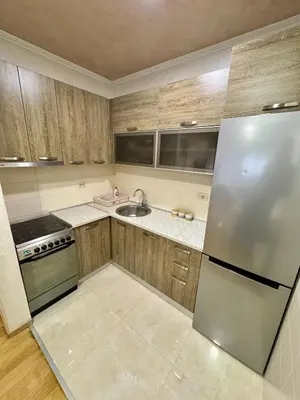 a kitchen with wooden cabinets and a stainless steel refrigerator at Modern City Apartment in Podgorica