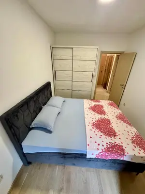a bedroom with a large bed with red flowers on it at Modern City Apartment in Podgorica