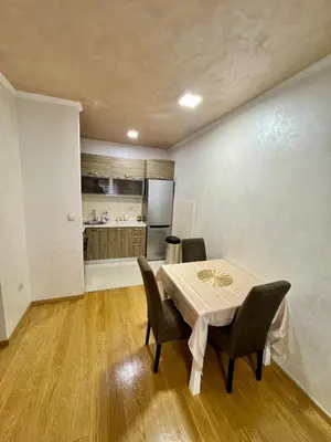 a dining room with a table and chairs and a kitchen at Modern City Apartment in Podgorica