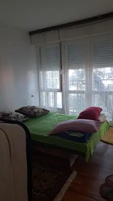 a bedroom with a bed with green sheets and windows at Apartmani Primorski hrast in Bar