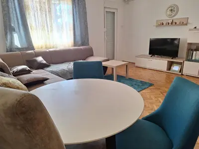 a living room with a white table and blue chairs at Guest house PG in Podgorica