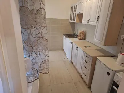 a kitchen with white cabinets and a shower curtain at Guest house PG in Podgorica
