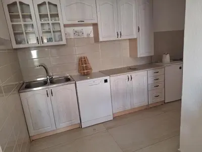 a white kitchen with white cabinets and a sink at Guest house PG in Podgorica