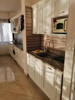 a kitchen with white cabinets and a sink and a microwave at Sun&Sea Apartments in Dobra Voda