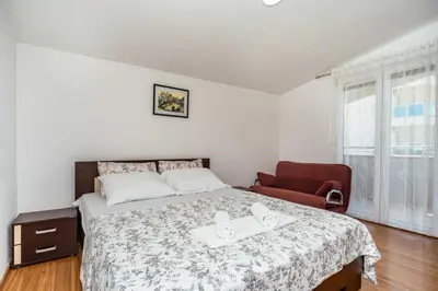 a bedroom with a bed and a red chair at Sea House Apartments in Bar
