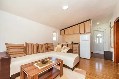 a living room with a white couch and a kitchen at Sea House Apartments in Bar