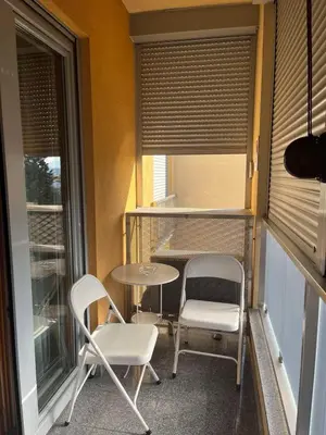 a balcony with two chairs and a table and a window at Central Podgorica Suite in Podgorica