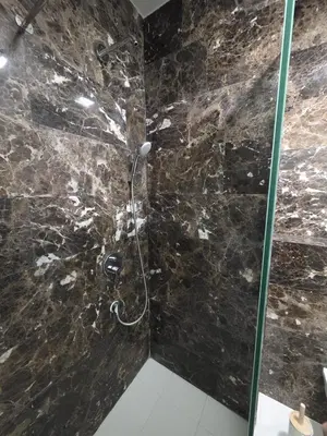 a shower in a bathroom with a black stone wall at Orenda Residences- Sea View Apartment in Budva