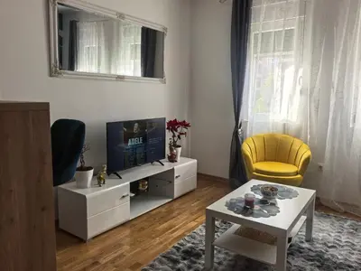 a living room with a tv and a yellow chair at relaxroom Podgorica in Podgorica