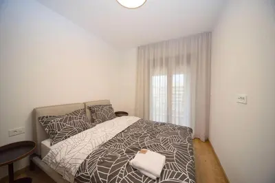 a bedroom with a bed and a table and a window at Premium apartments with garage in Podgorica
