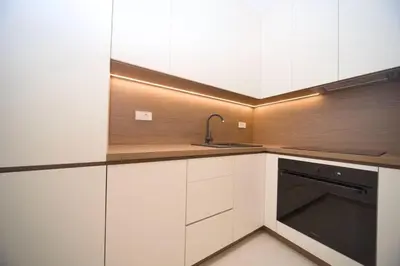 a kitchen with white cabinets and a black dishwasher at Premium apartments with garage in Podgorica