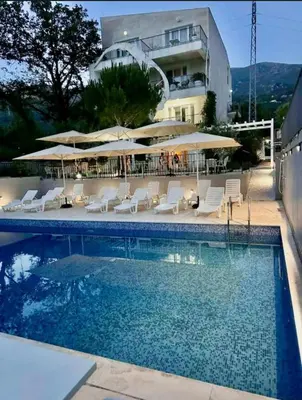 a swimming pool with chairs and umbrellas next to a building at Val Apartment, Przno in Budva