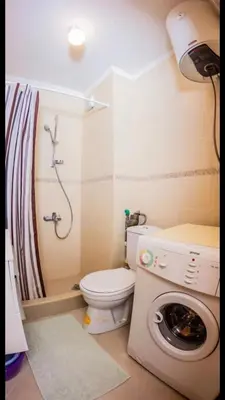 a bathroom with a toilet and a washing machine at Квартира in Budva