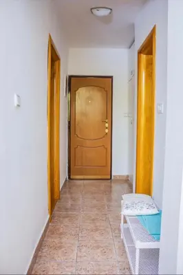 a hallway with a wooden door and a chair at Квартира in Budva