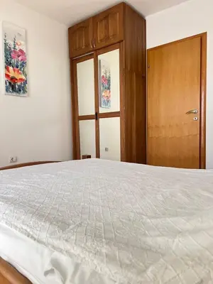 a bedroom with a large bed and a wooden cabinet at Квартира in Budva