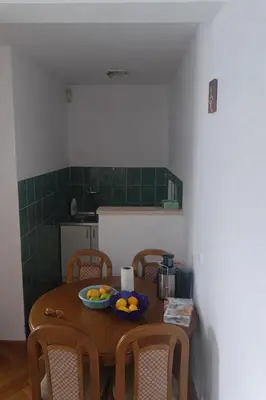 a kitchen with a table with a bowl of fruit on it at Apartman Vuk in Rafailovici