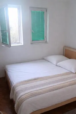 two beds in a white room with two windows at Apartman Vuk in Rafailovici