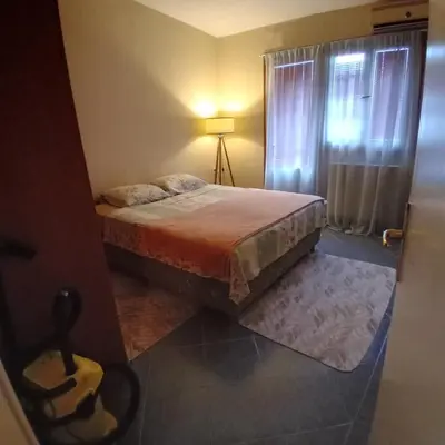 a bedroom with a bed with a lamp and a window at Podgorica apartment in Podgorica