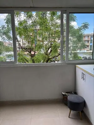 a room with three windows and a stool and a tree at LuxeStay Ksenija apartment in Podgorica
