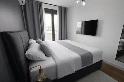 a bedroom with a large bed with a window at Urban Forest Apartment - with free Garage in Podgorica