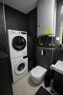 a bathroom with a washing machine and a toilet at Urban Forest Apartment - with free Garage in Podgorica