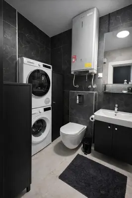 a bathroom with a washing machine and a sink at Urban Forest Apartment - with free Garage in Podgorica