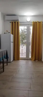 a living room with yellow curtains and a refrigerator at Amore Studio Apartment in Bar, Susanj