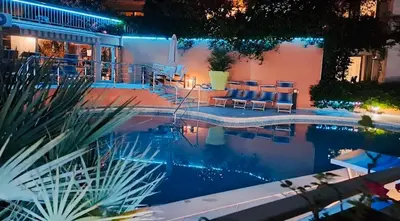 a swimming pool at night with chairs and a patio at Njaro del Mar Petrovac Bay in Petrovac na Moru