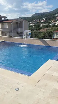 a swimming pool with a fountain in front of a house at Apartments Villa Royale in Dobra Voda
