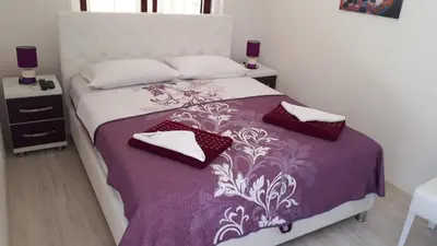a bedroom with a bed with a purple and white bedspread at Apartments Villa Royale in Dobra Voda