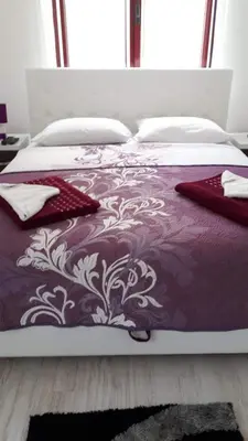 a large bed with a purple and white bedspread at Apartments Villa Royale in Dobra Voda