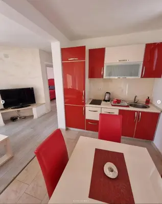 a kitchen with red cabinets and a table and red chairs at Apartments Villa Royale in Dobra Voda