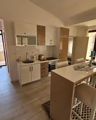 a kitchen with white cabinets and a table with chairs at Apartments Villa Royale in Dobra Voda