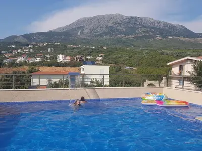 a person in a swimming pool with a mountain in the background at Apartments Villa Royale in Dobra Voda