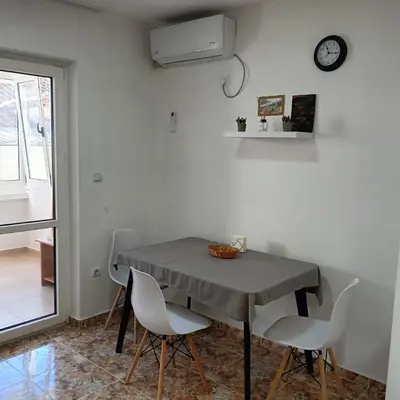 a dining room table with chairs and a clock on the wall at Veli Vinogradi in Budva
