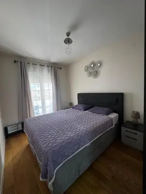 a bedroom with a bed with purple sheets and a window at Urban Stay in Podgorica