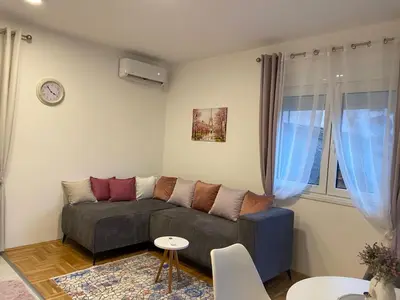 a living room with a couch and a clock on the wall at Jednosoban namješten stan - Cetinje in Cetinje