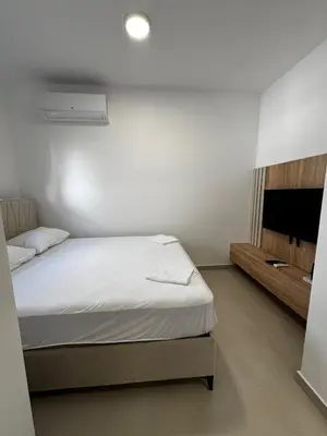 a bedroom with a white bed and a television at Mayne Apartmant in Budva