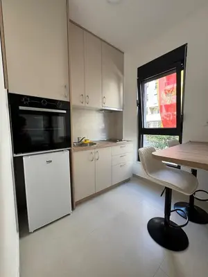 a kitchen with a white refrigerator and a table with a chair at Mayne Apartmant in Budva