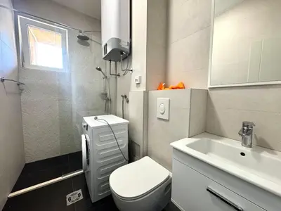 a bathroom with a white toilet and a sink at The Government District Suite in Podgorica