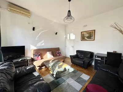 a living room with a leather couch and a tv at The Government District Suite in Podgorica